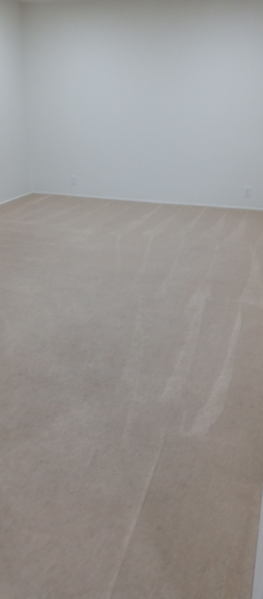 A large empty room with a beige floor and white walls.