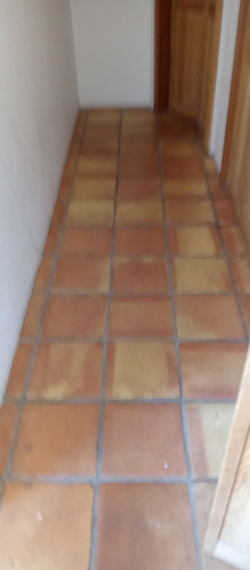A tiled floor in a hallway next to a door.