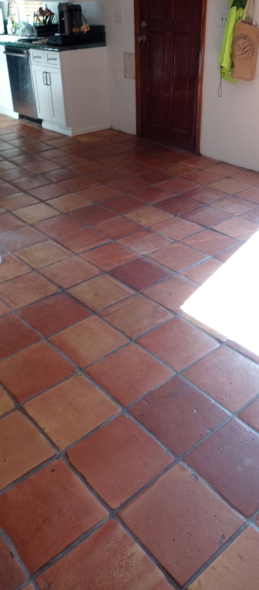 A kitchen with a tiled floor and a wooden door.