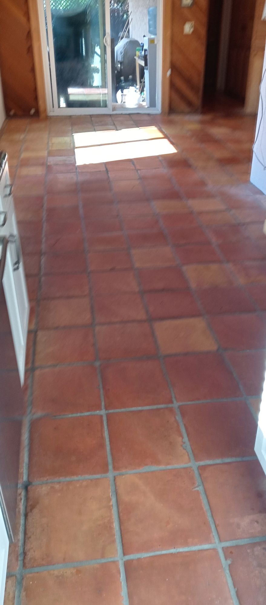 A kitchen with a tiled floor and a sliding glass door.
