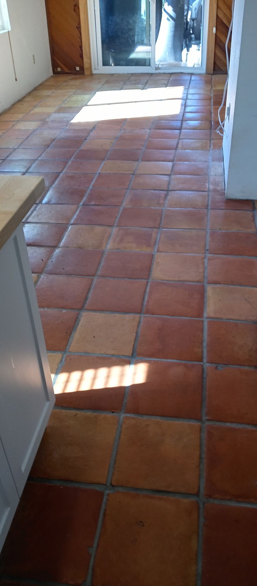 A kitchen with a tiled floor and a sliding glass door.