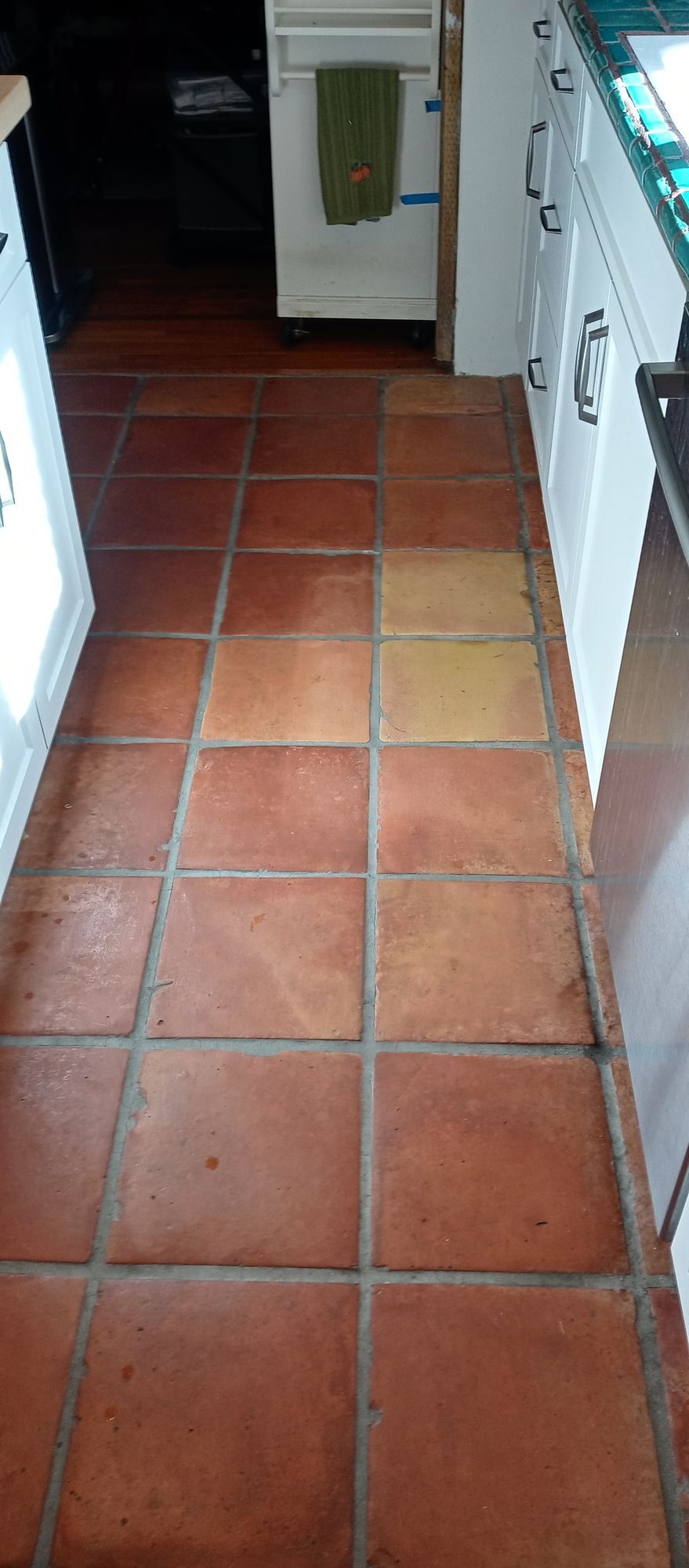 A kitchen with red tile floors and white cabinets.