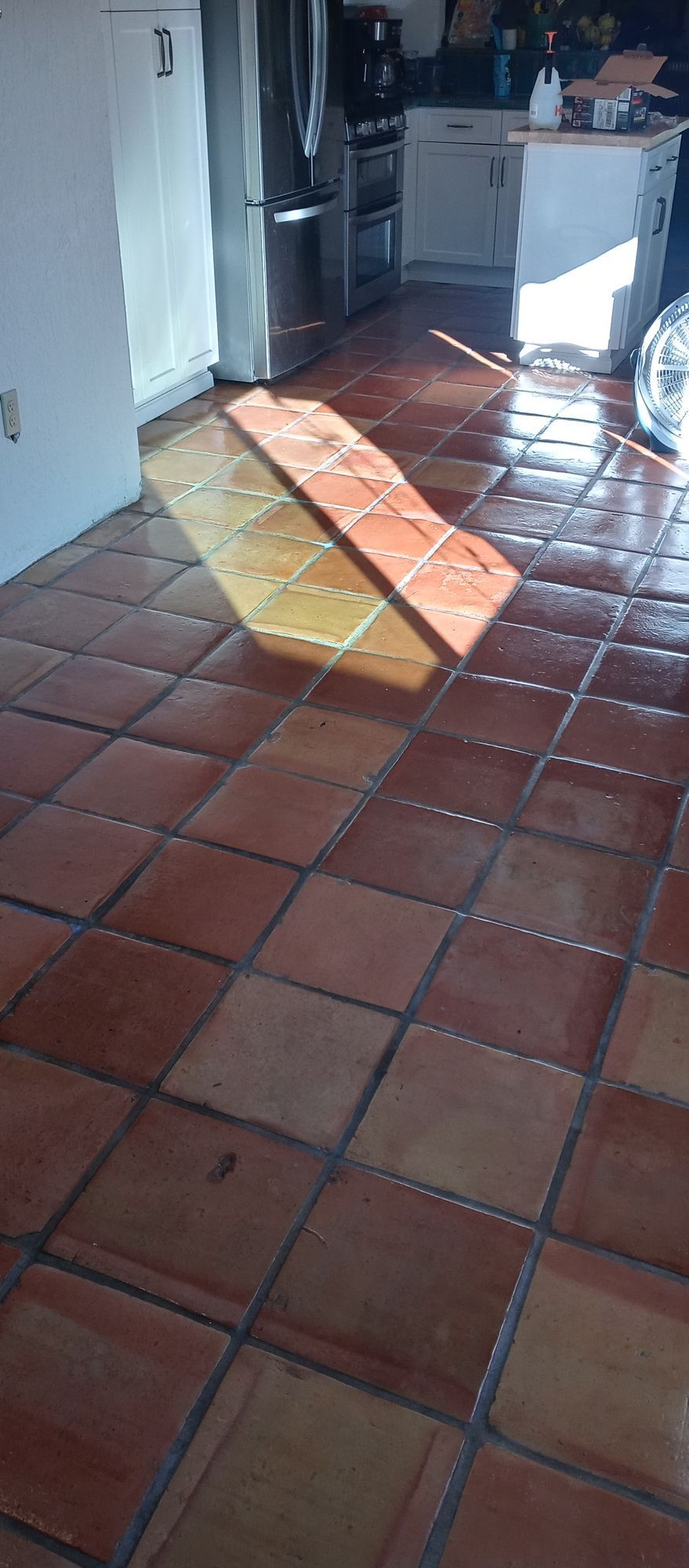 A kitchen with a tiled floor and a refrigerator.