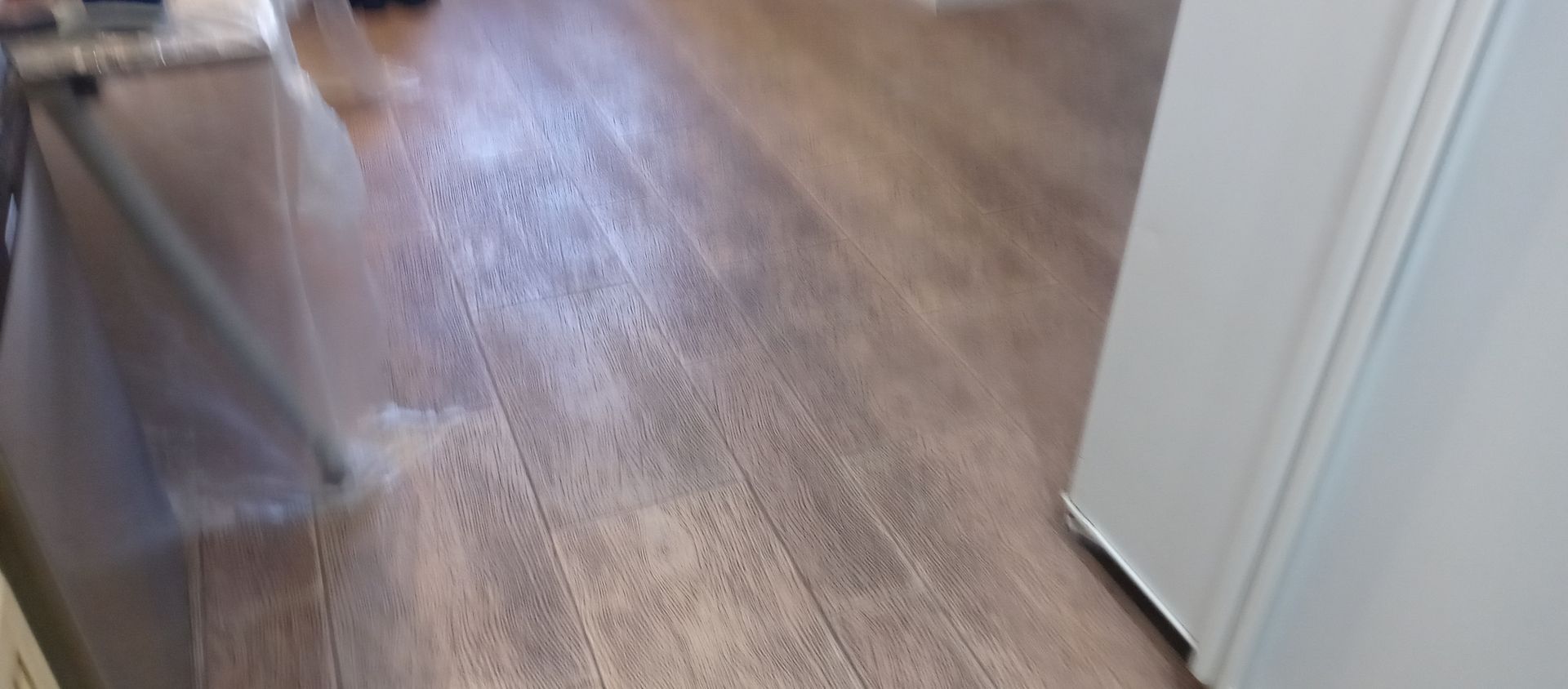 A person is cleaning a wooden floor with a vacuum cleaner.