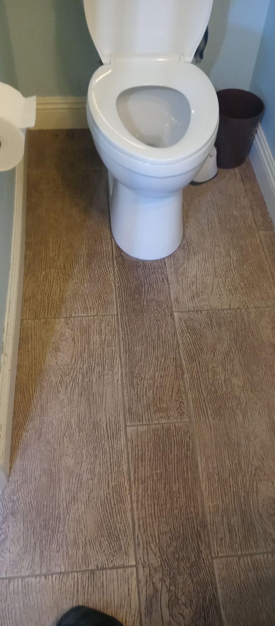 A toilet is sitting on a tiled floor in a bathroom.