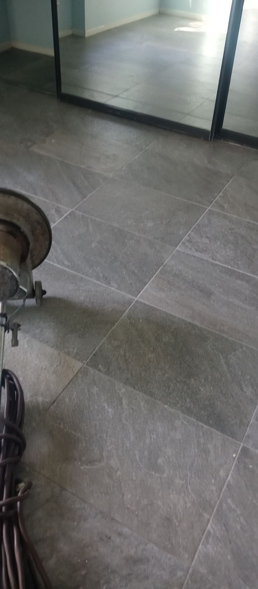 A drum set is sitting on a tiled floor next to a mirror.