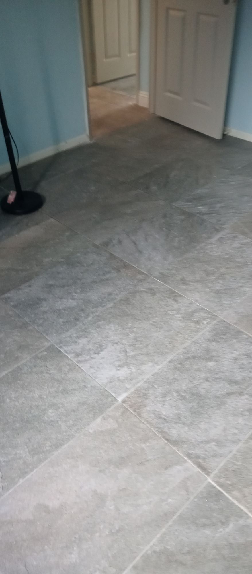 A vacuum cleaner is sitting on a tiled floor in a room next to a door.