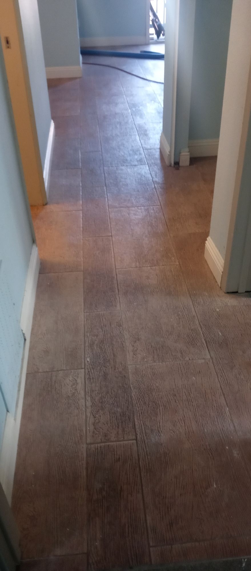 A hallway with a tiled floor and a doorway leading to another room.