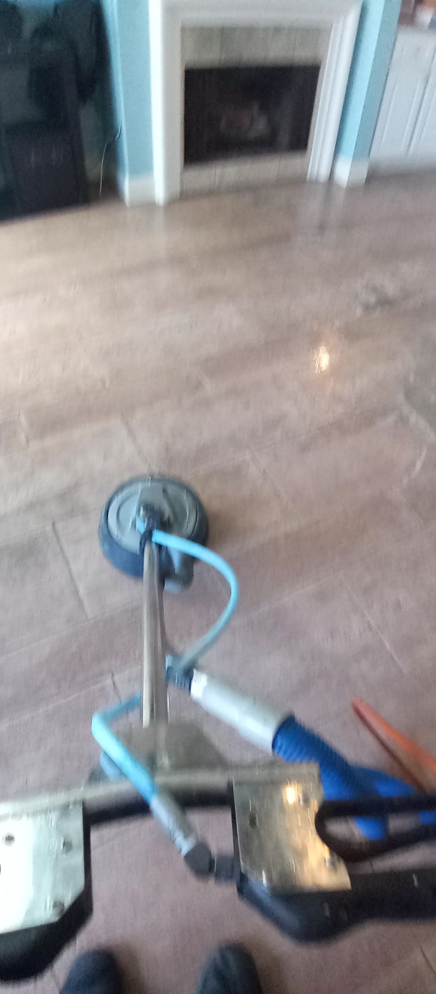 A person is standing on a wooden floor with a tool on it.