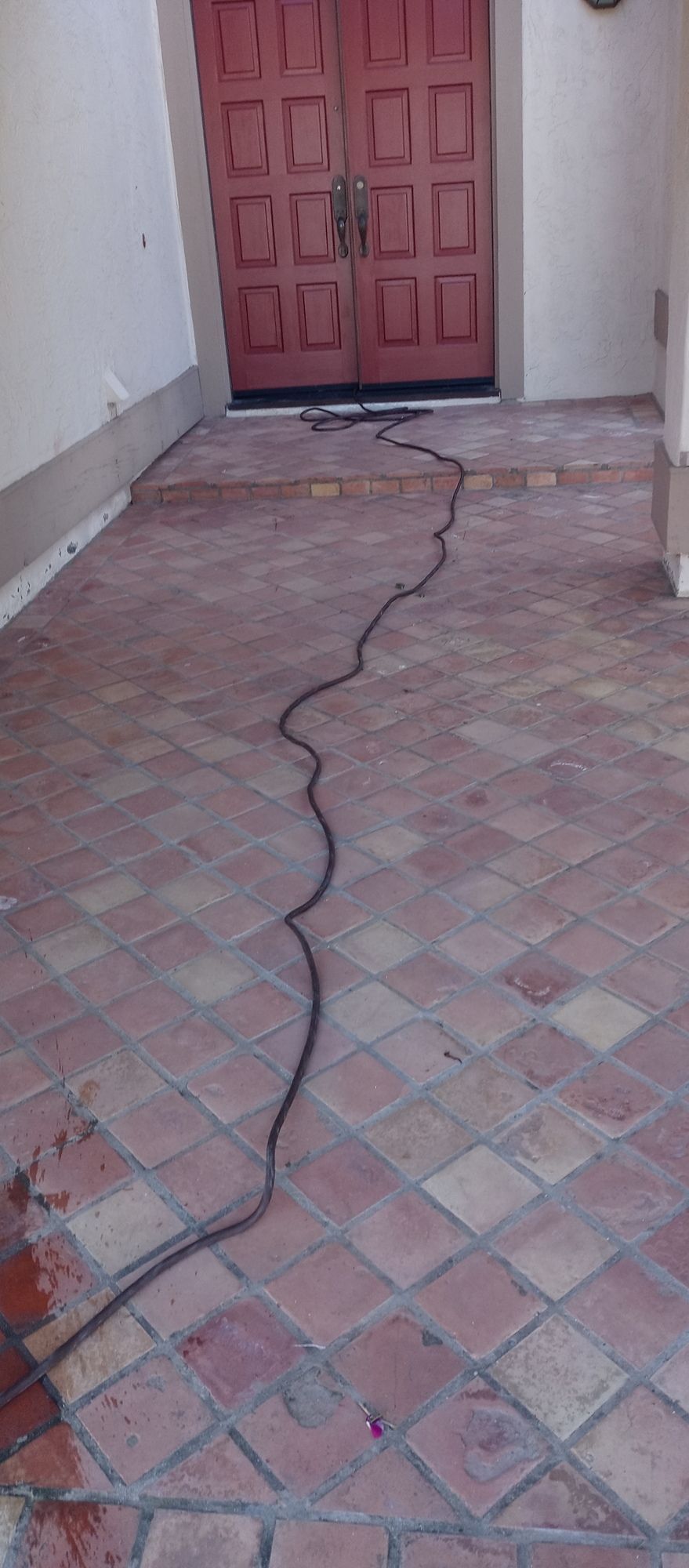 a red tiled floor with cleaning material and long cable