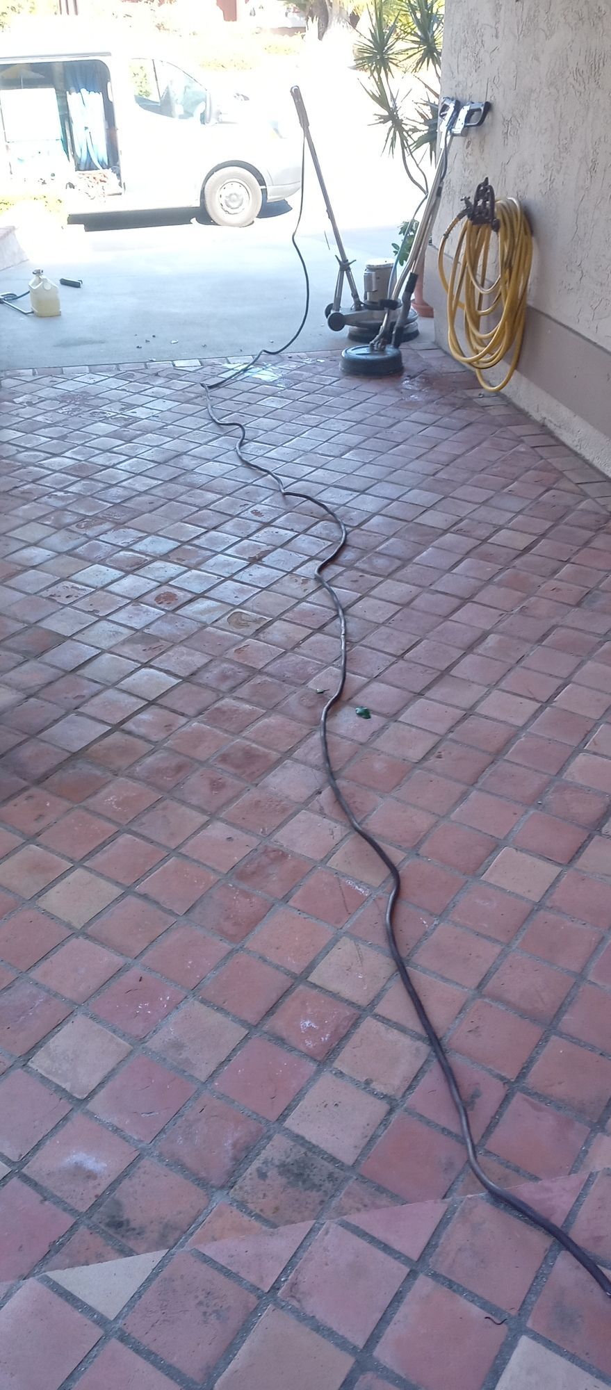 A vacuum cleaner is sitting on a brick floor in a garage.