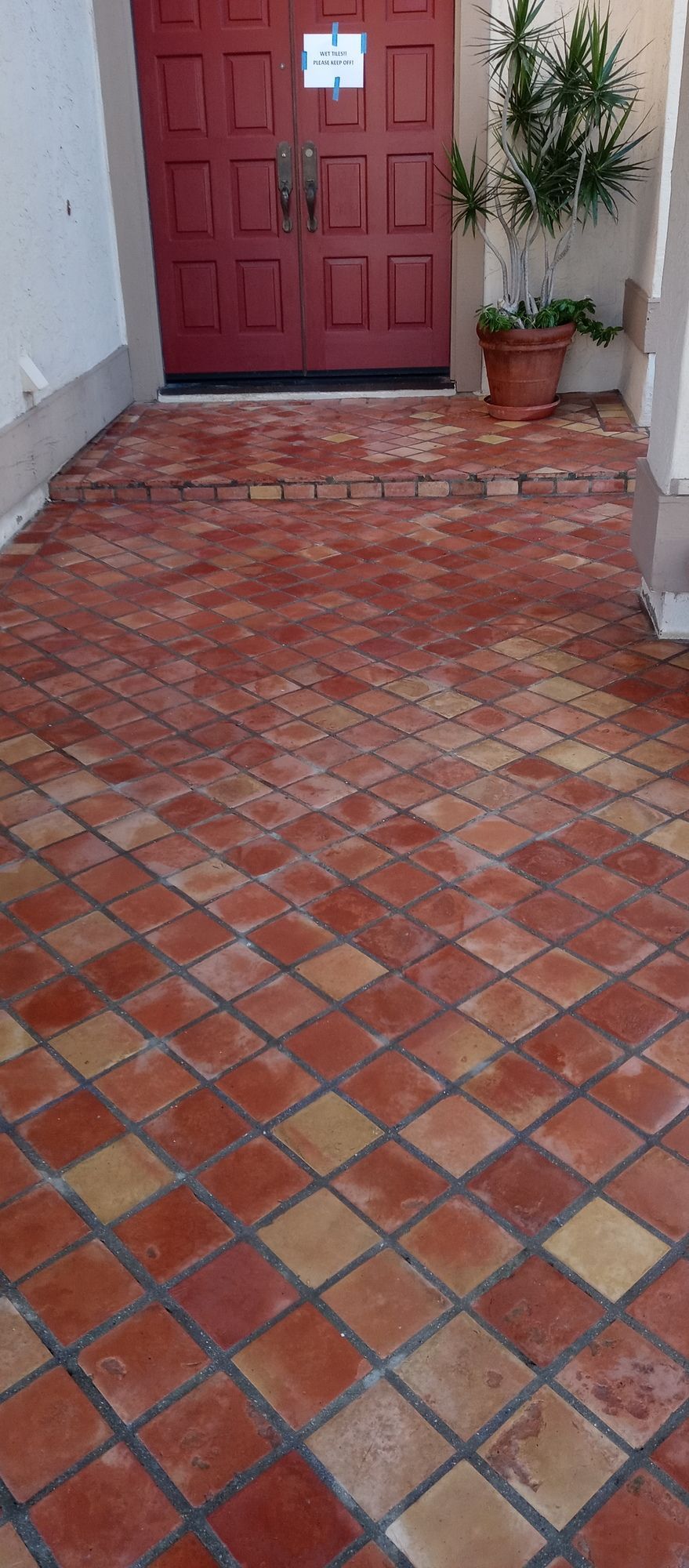 A brick floor with a red door in the background.