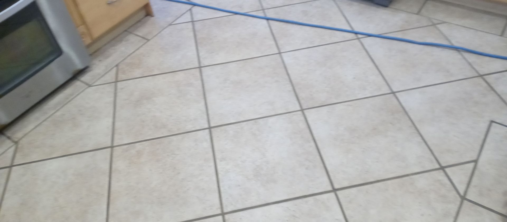 A tiled floor in a kitchen with a stove in the background