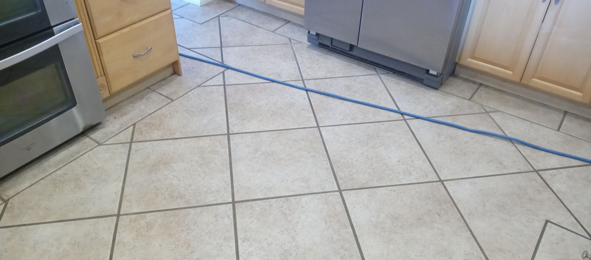 A kitchen with a tiled floor , a stove and a refrigerator.