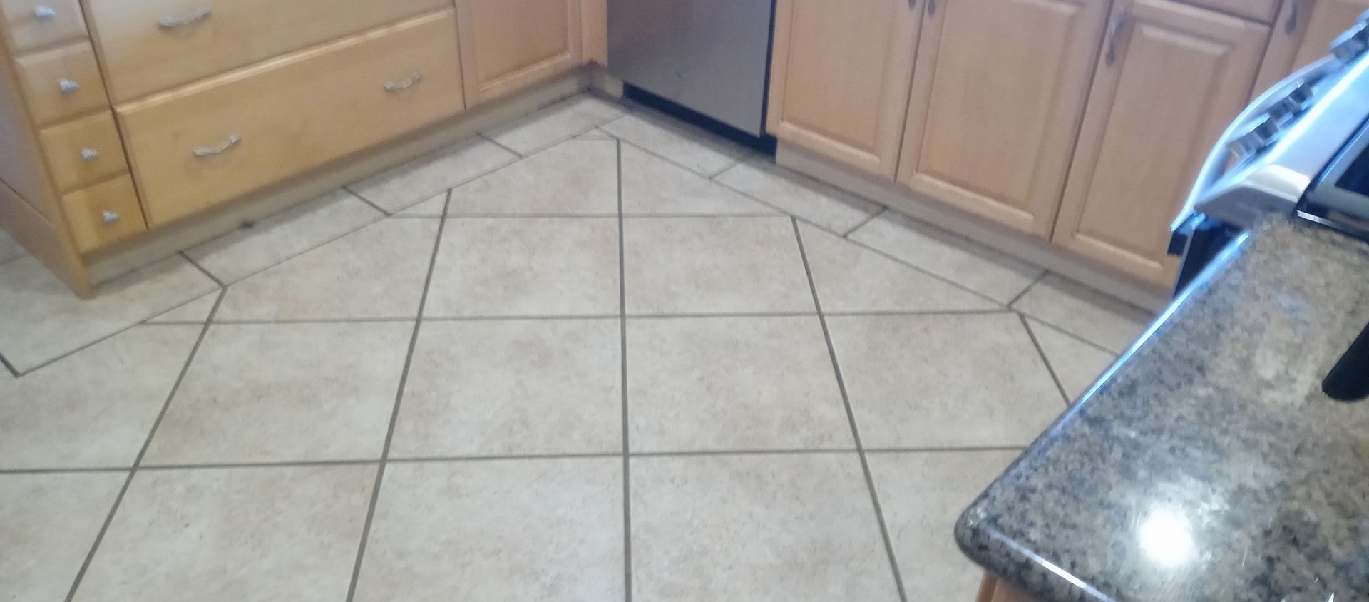 A kitchen with tile floors and wooden cabinets