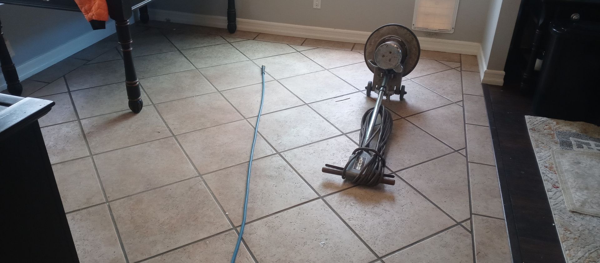 A fan is sitting on a tiled floor in a living room.