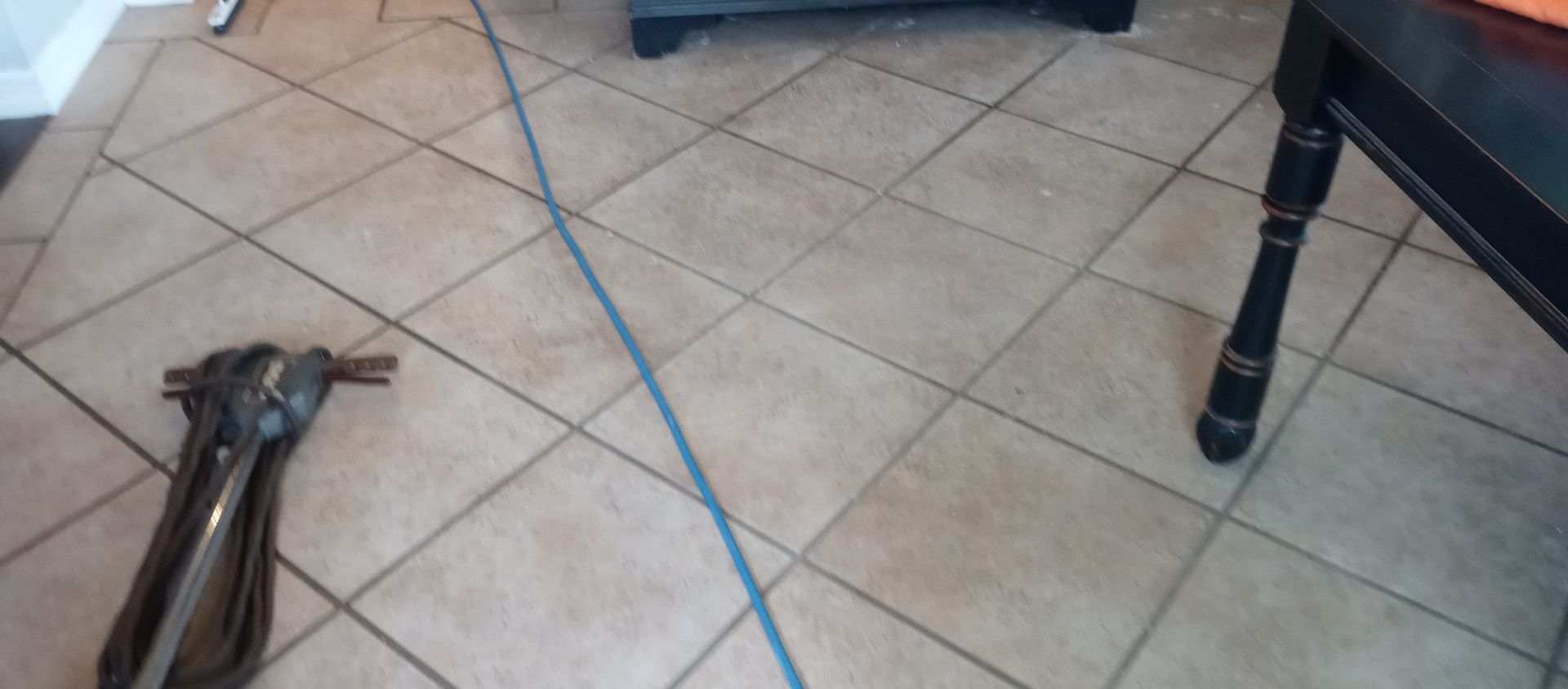 A vacuum cleaner is sitting on a tiled floor next to a table.