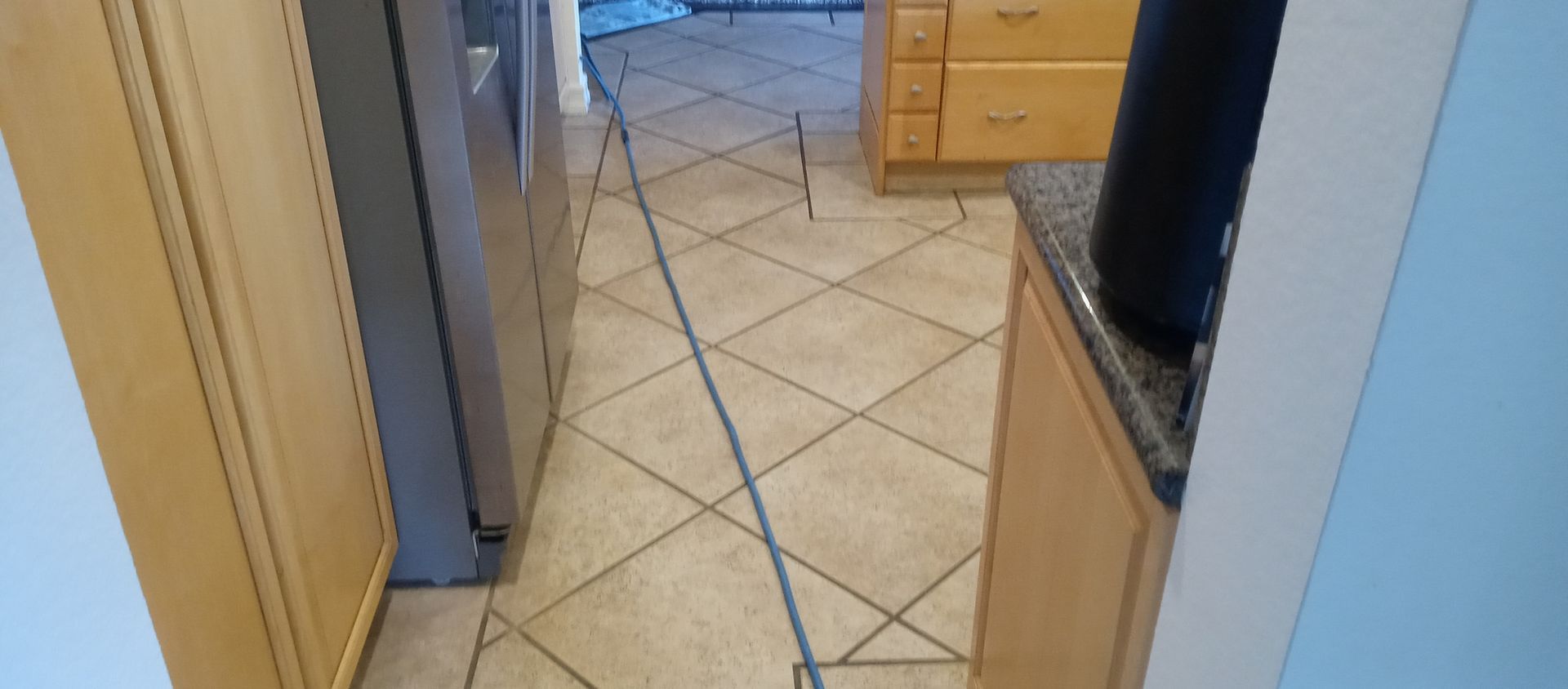 A kitchen with a tiled floor and a refrigerator.