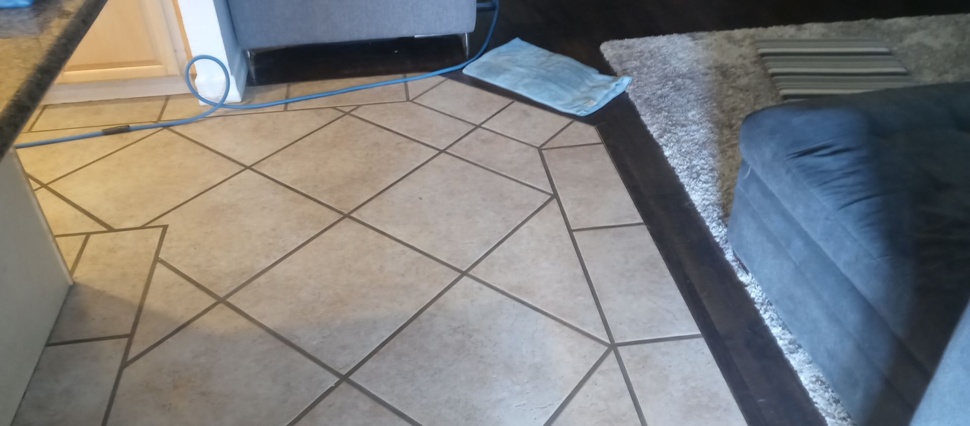 A tiled floor in a living room next to a couch.