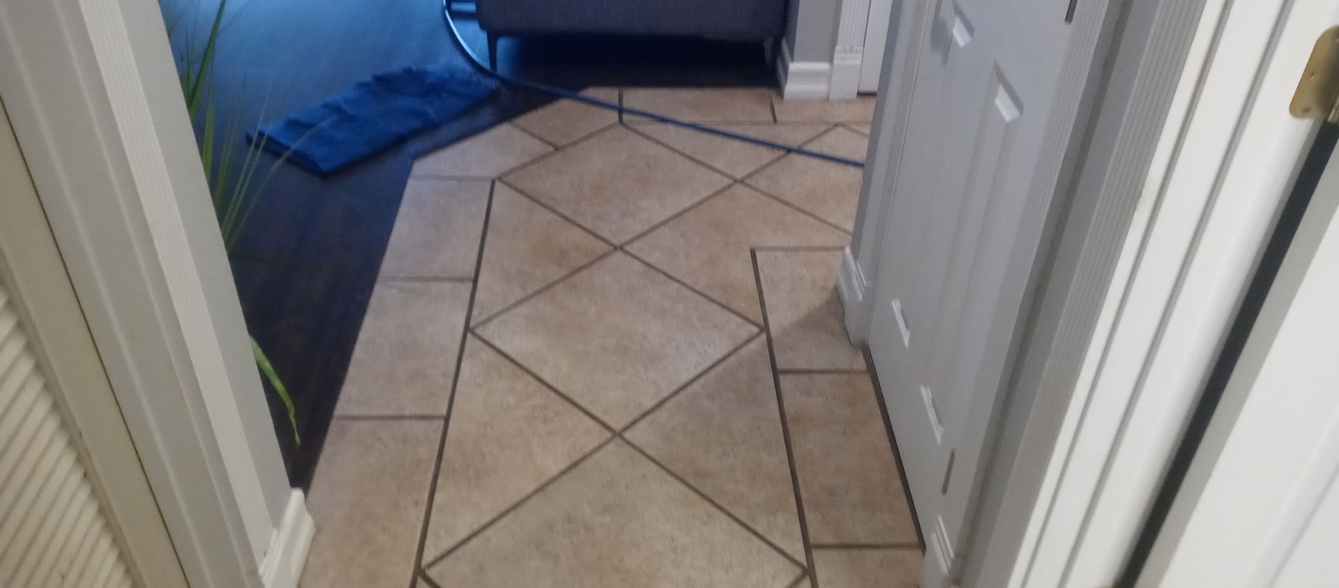 A hallway with a tiled floor and a door leading to a bathroom.