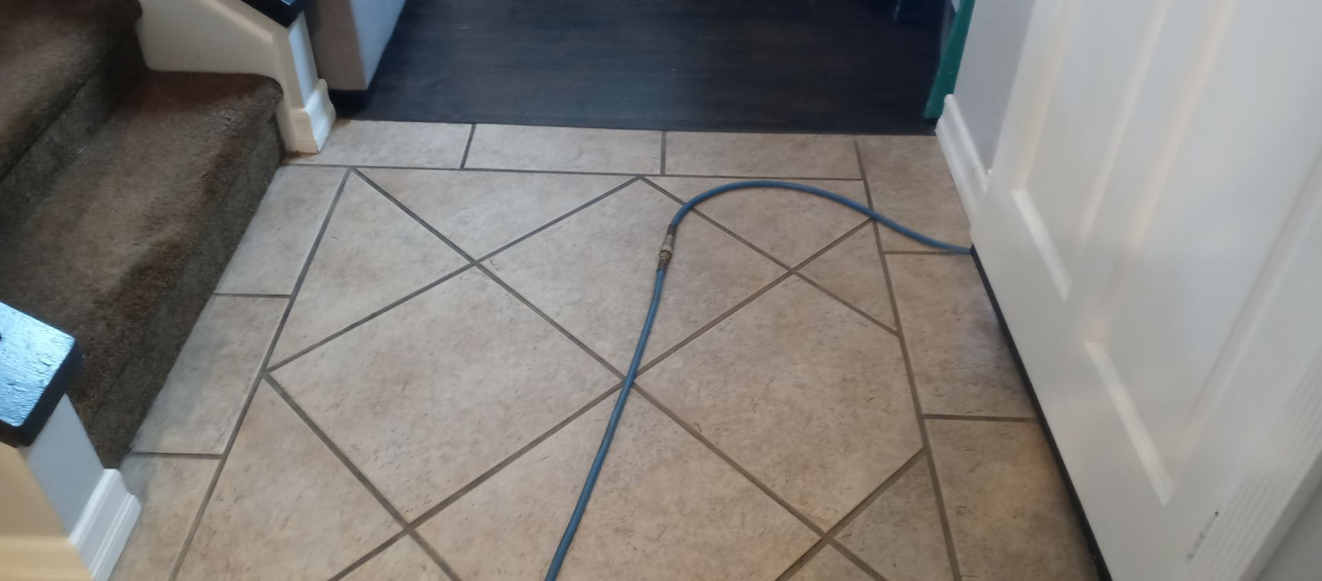 A blue cord is laying on a tiled floor next to a door.