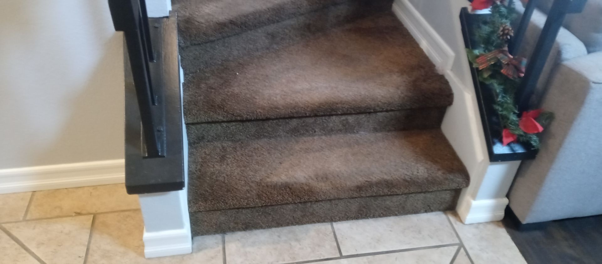 A staircase with a brown carpet and a black railing in a house.