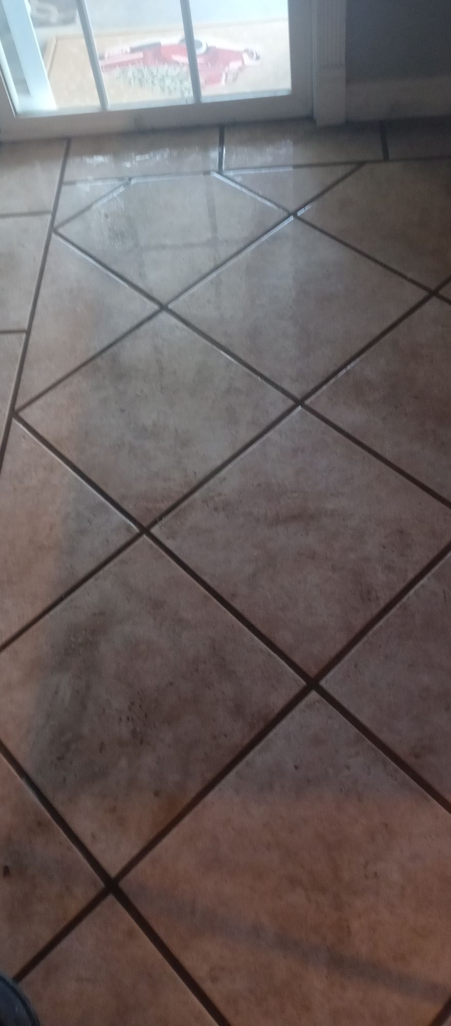 A close up of a tiled floor with a window in the background.