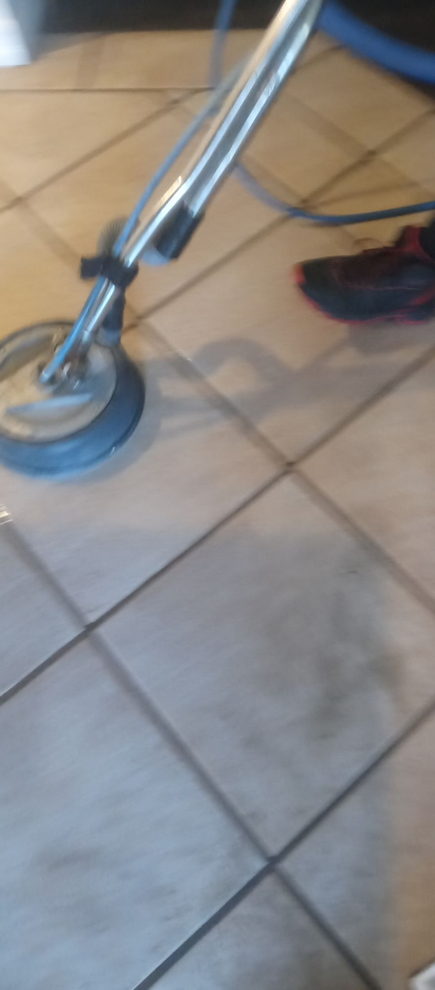 A person is cleaning a tile floor with a machine.