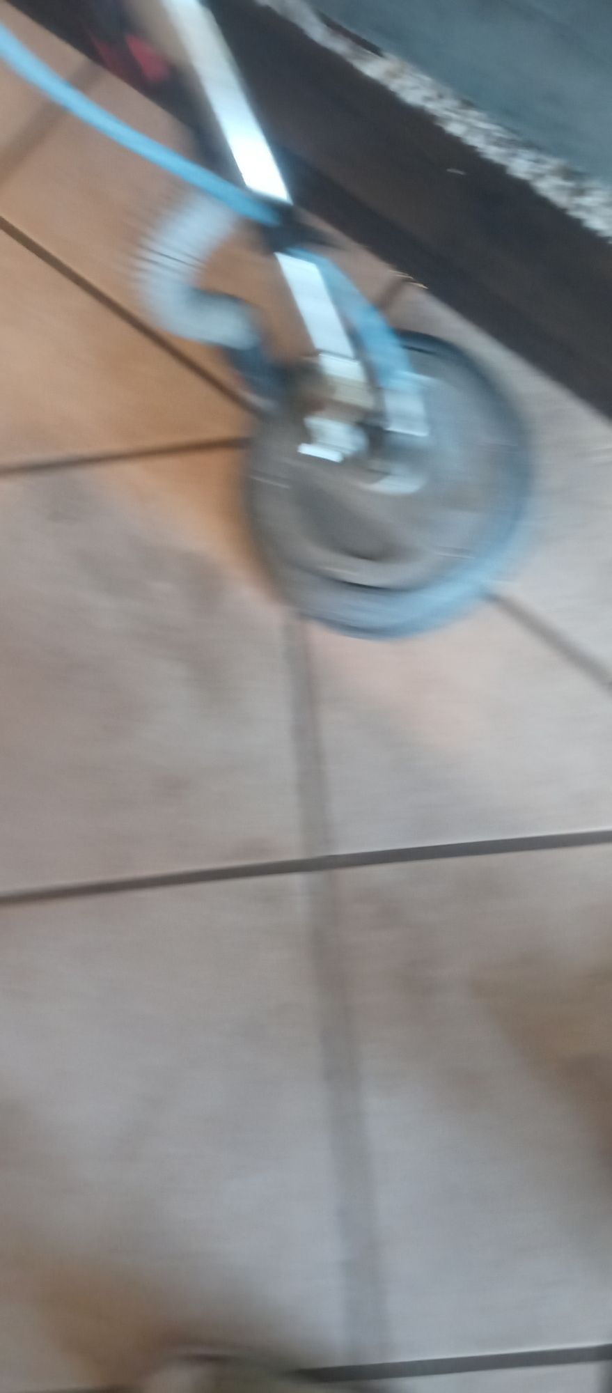 A person is cleaning a tile floor with a vacuum cleaner.