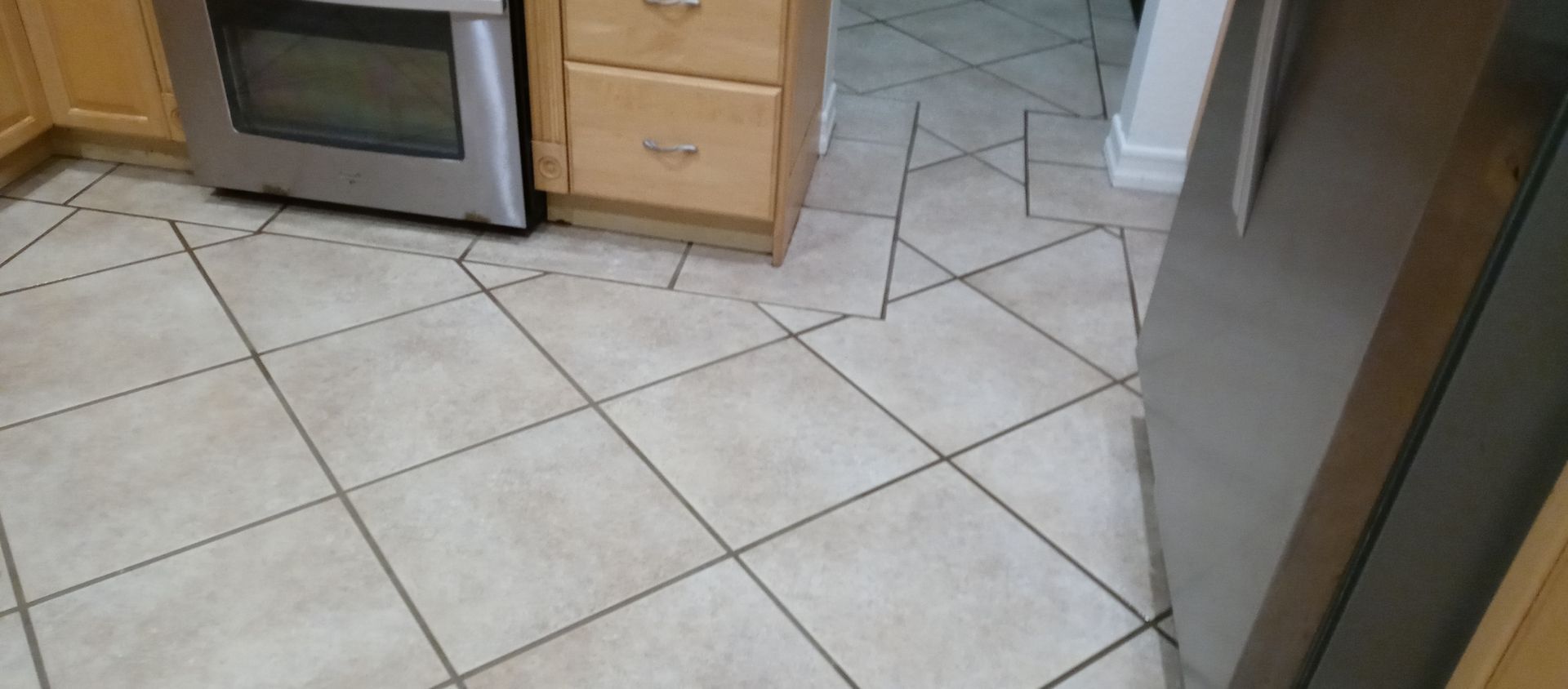 A kitchen with a tiled floor and a stainless steel refrigerator.