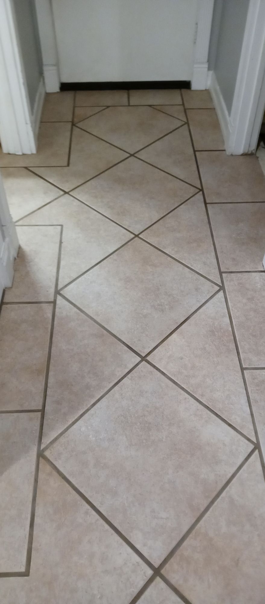 A tiled floor in a hallway with a door in the background.