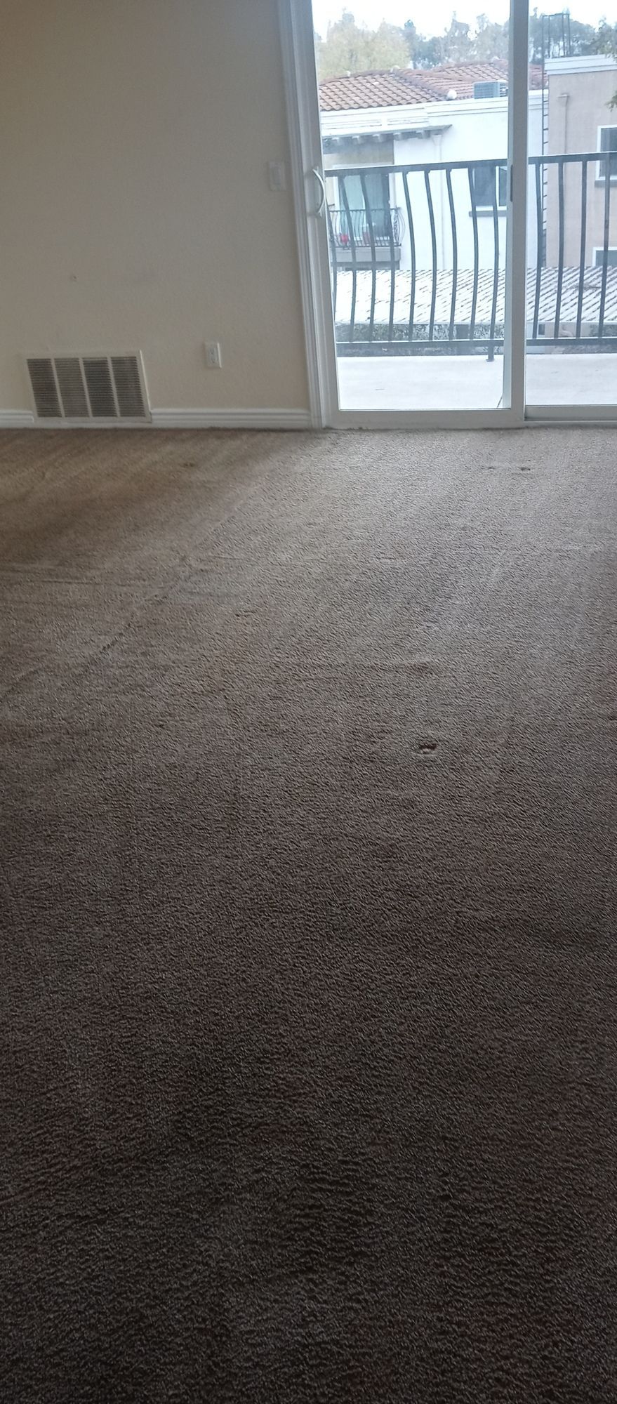 An empty living room with a sliding glass door and a balcony.