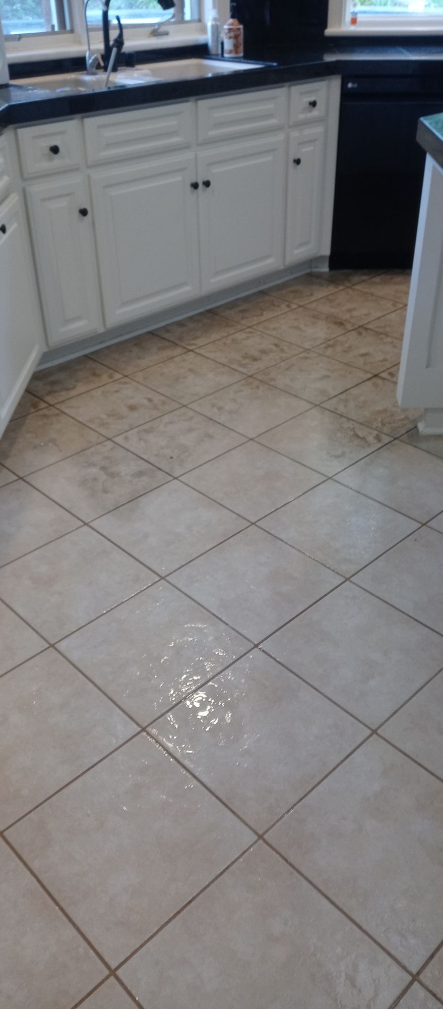 A kitchen with white cabinets and a tile floor.