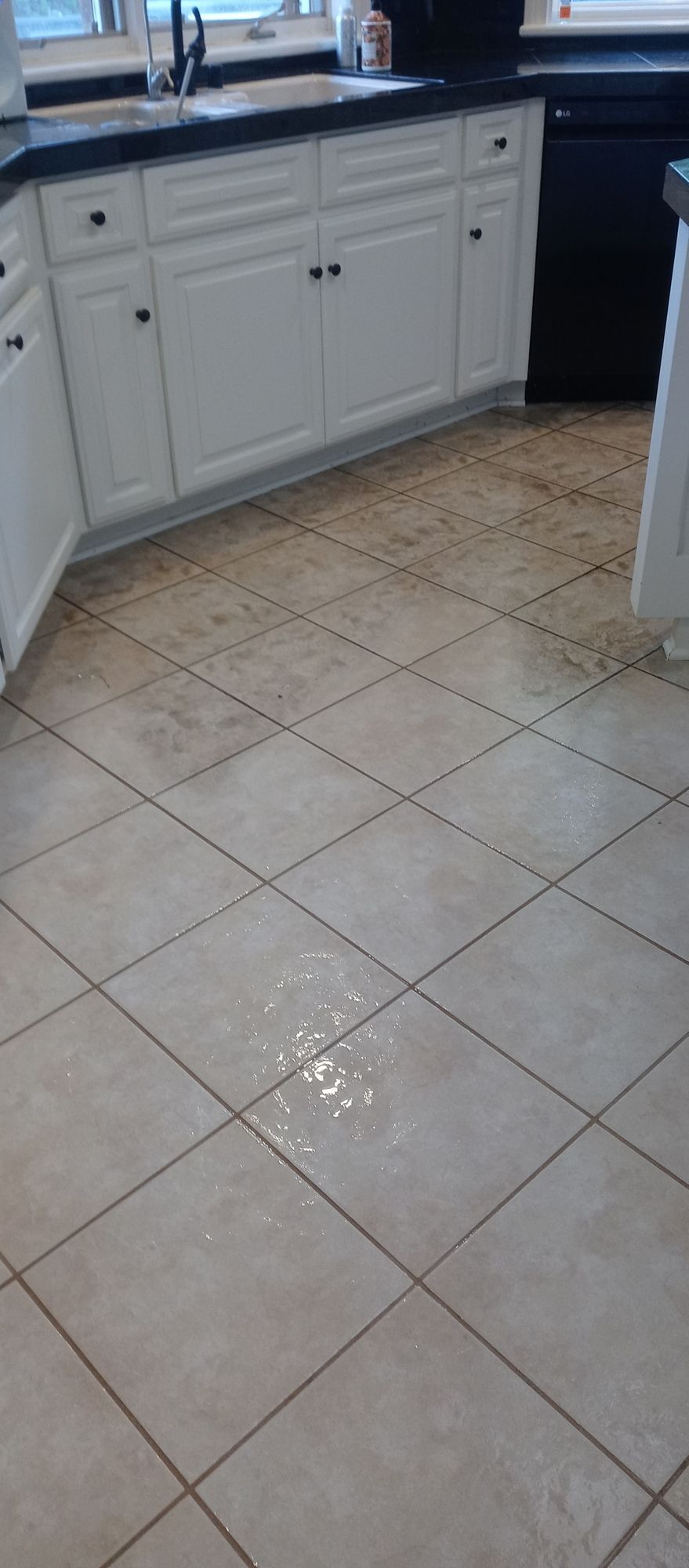 A kitchen with white cabinets and a tile floor.