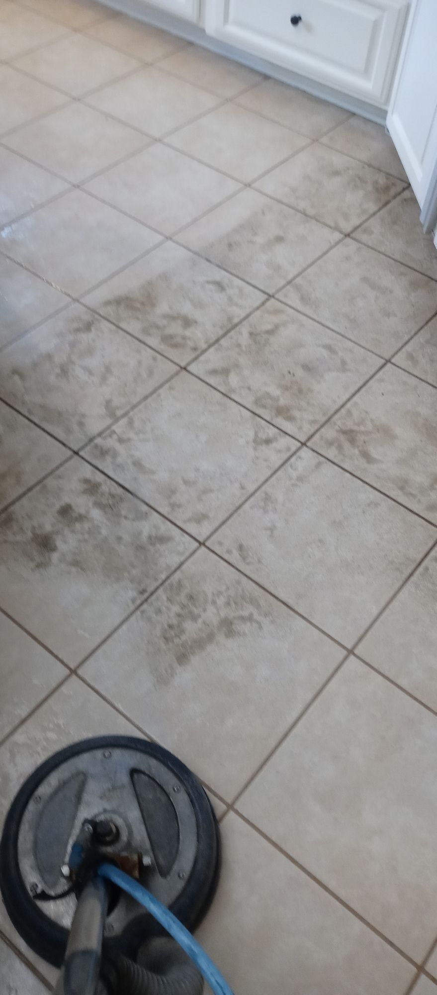 A tile floor is being cleaned with a vacuum cleaner.