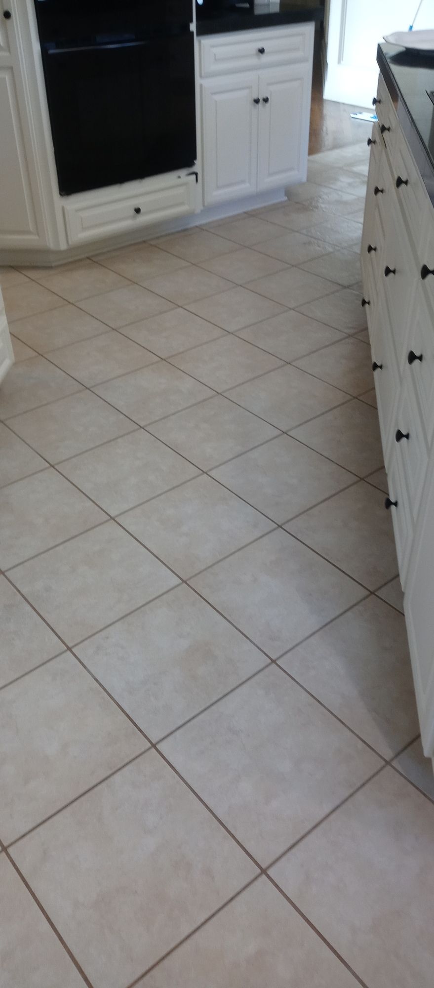 A kitchen with white cabinets and a tile floor.