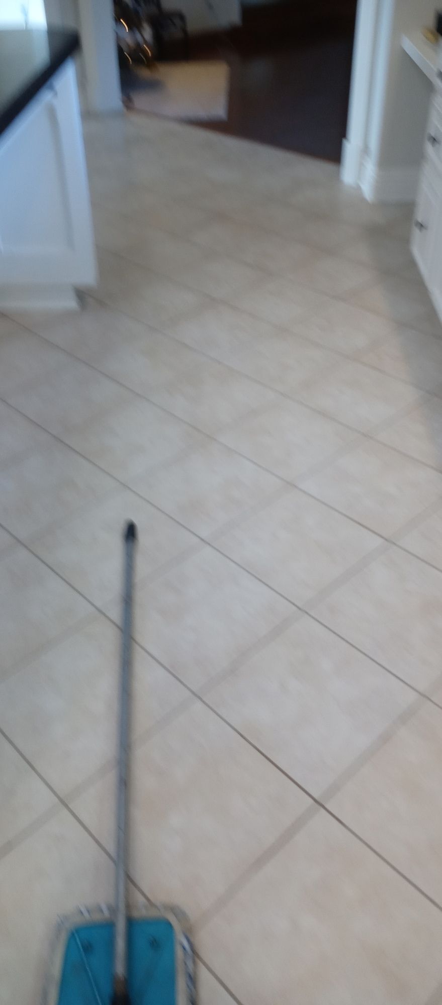 A mop is sitting on a tiled floor in a kitchen.