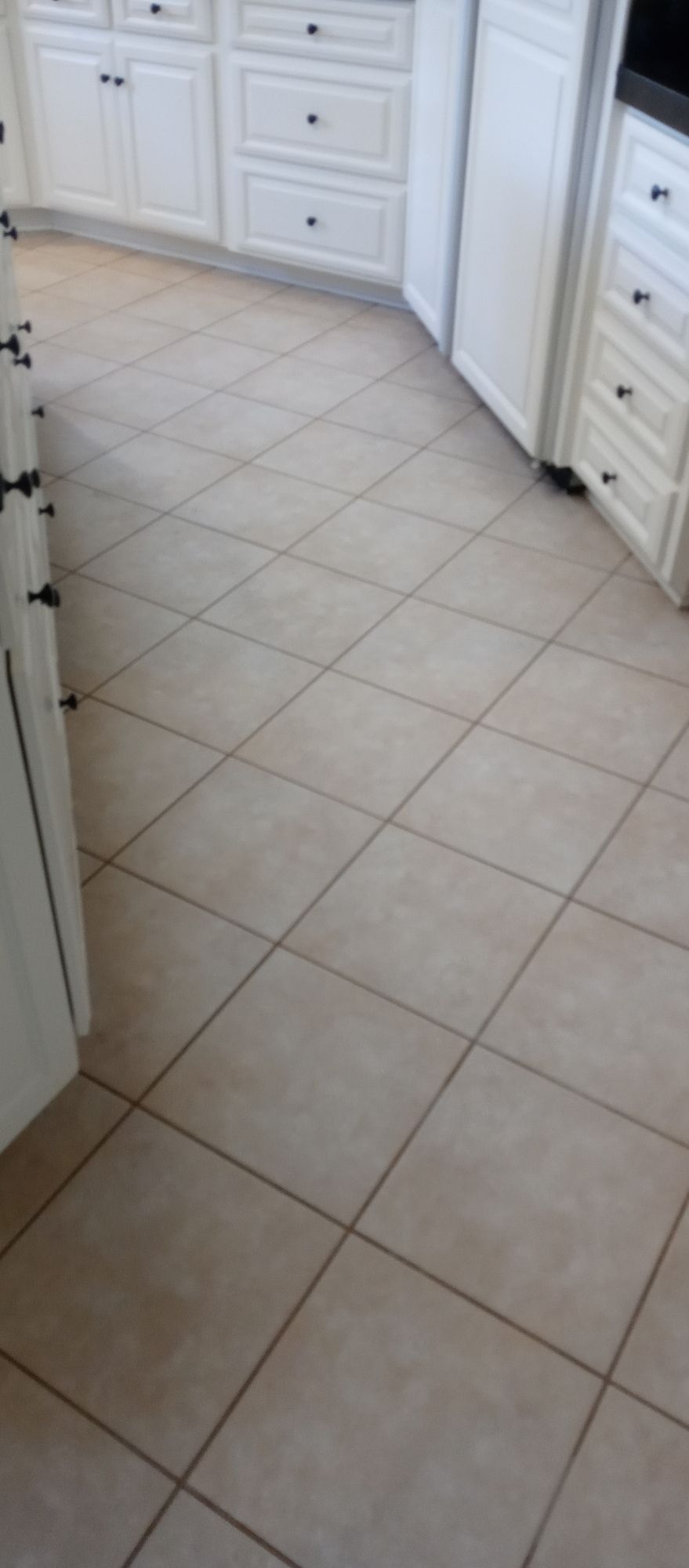 A kitchen with white cabinets and tile floors.