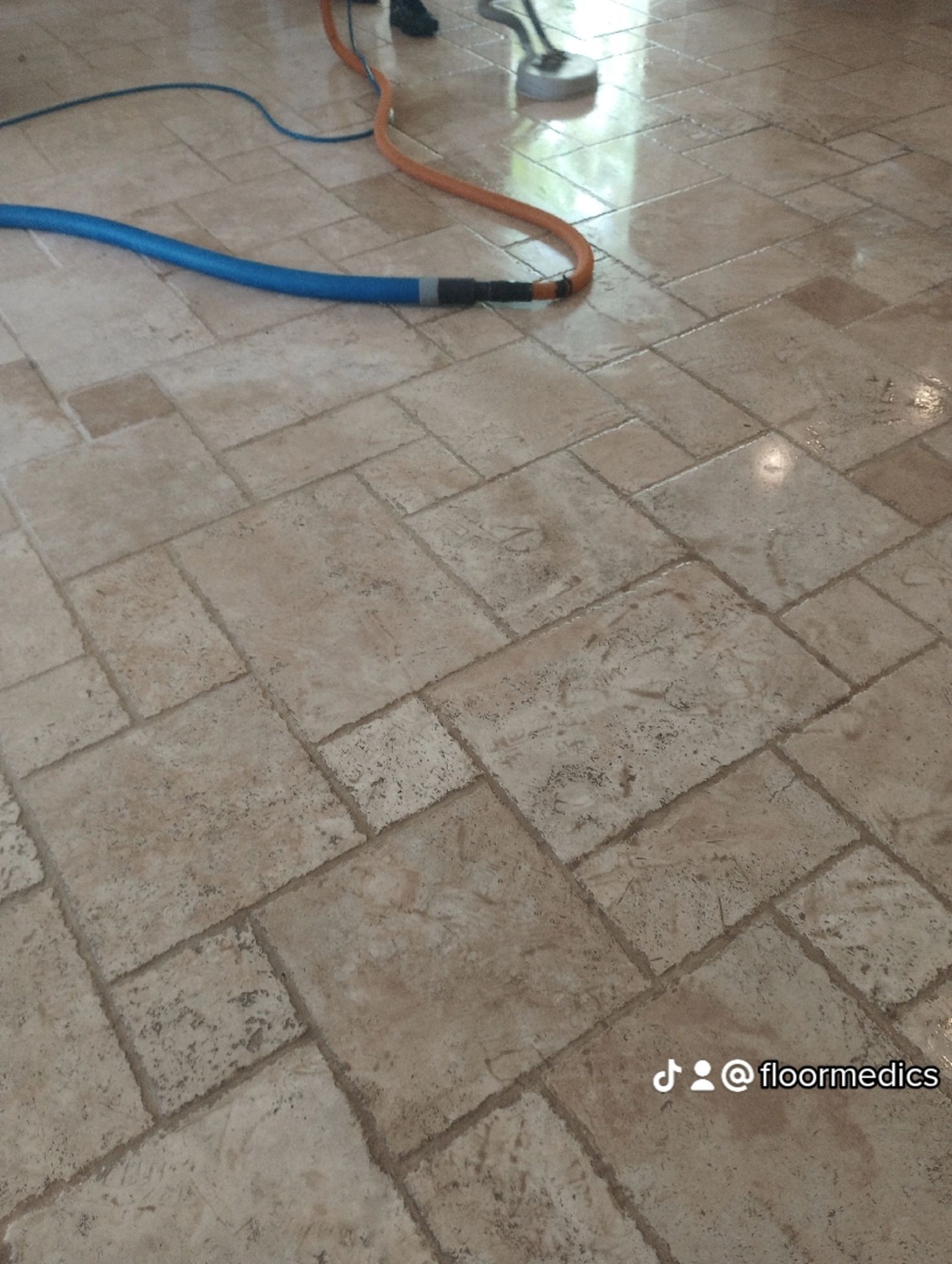 A tile floor with a vacuum cleaner attached to it.