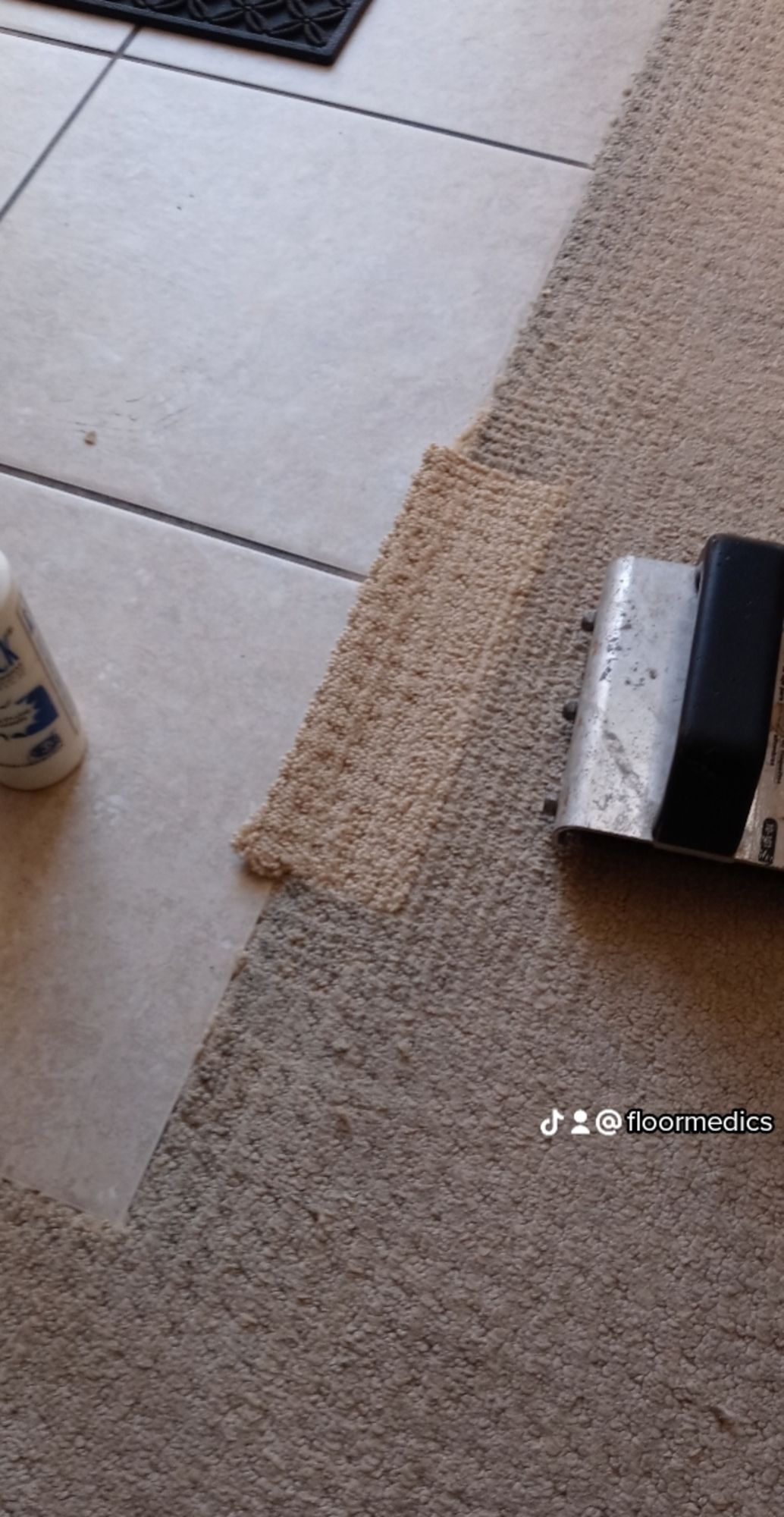 A vacuum cleaner is cleaning a carpet on a tiled floor.
