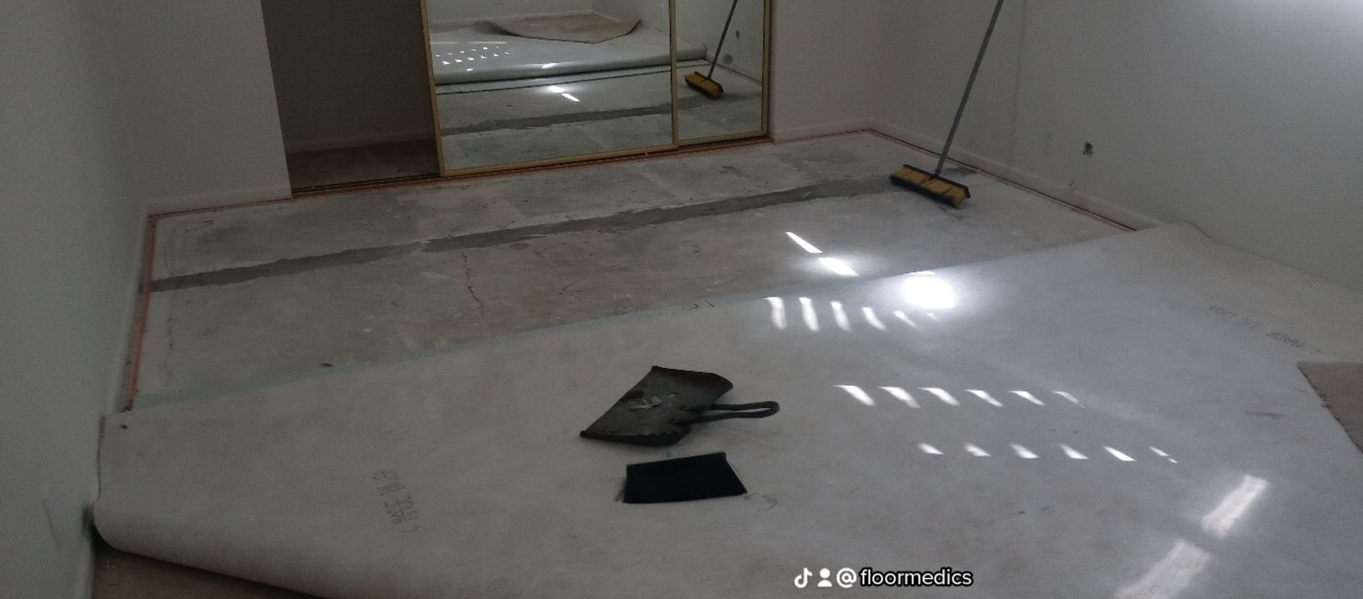 A room with a carpet on the floor and a broom.