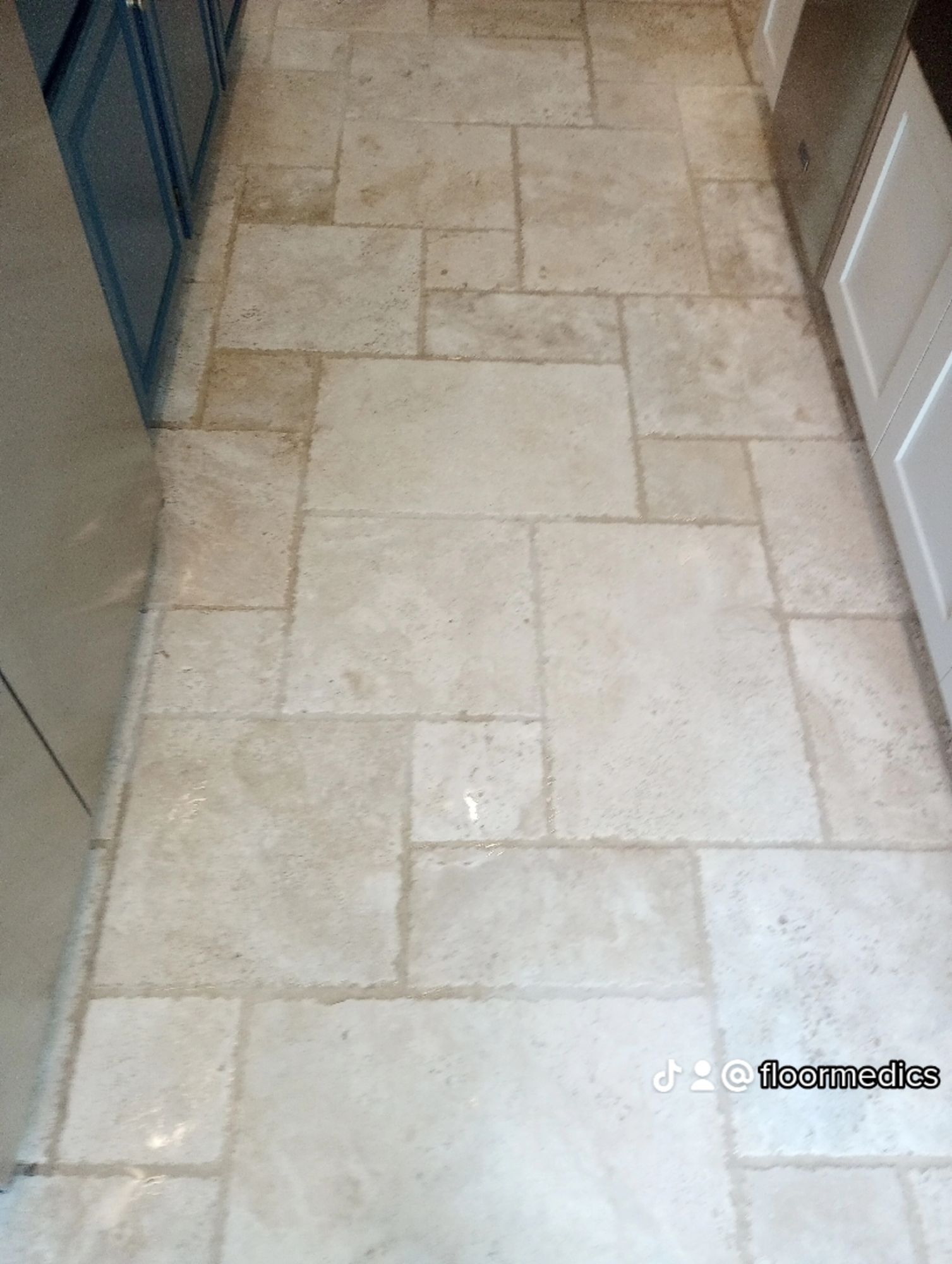A kitchen with a tile floor and white cabinets