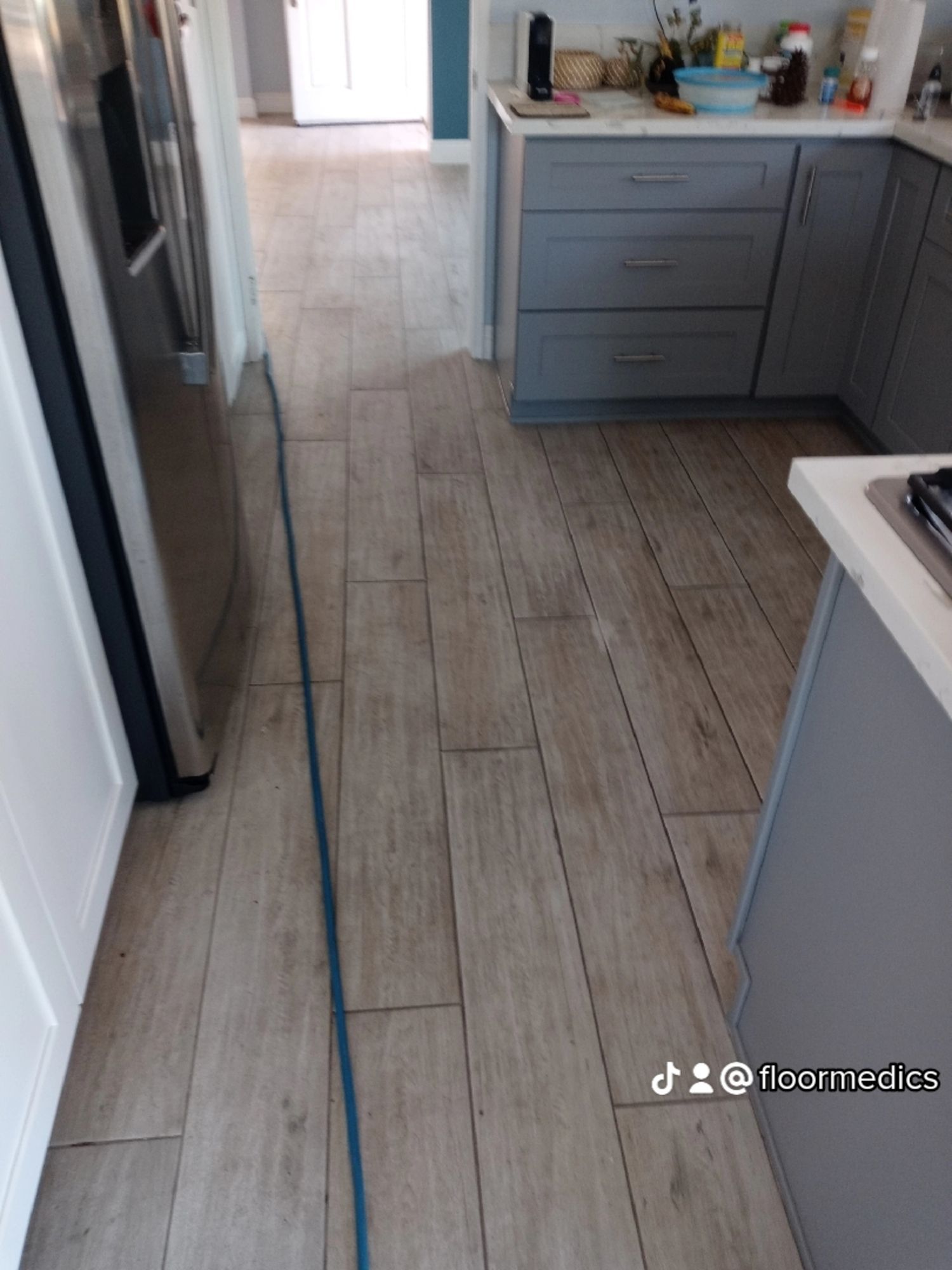 A kitchen with a wooden floor and a blue hose