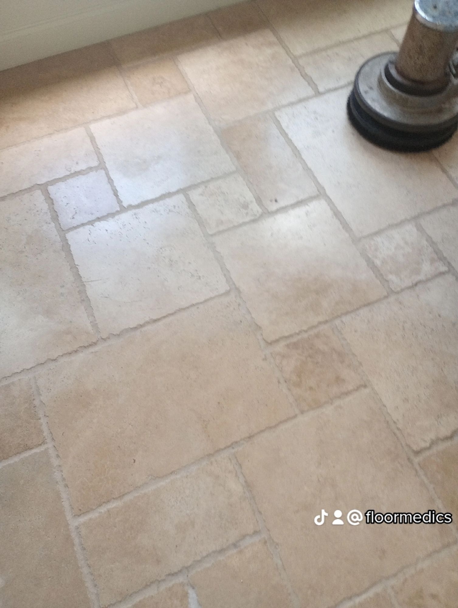 A close up of a tiled floor with a vacuum cleaner on it.