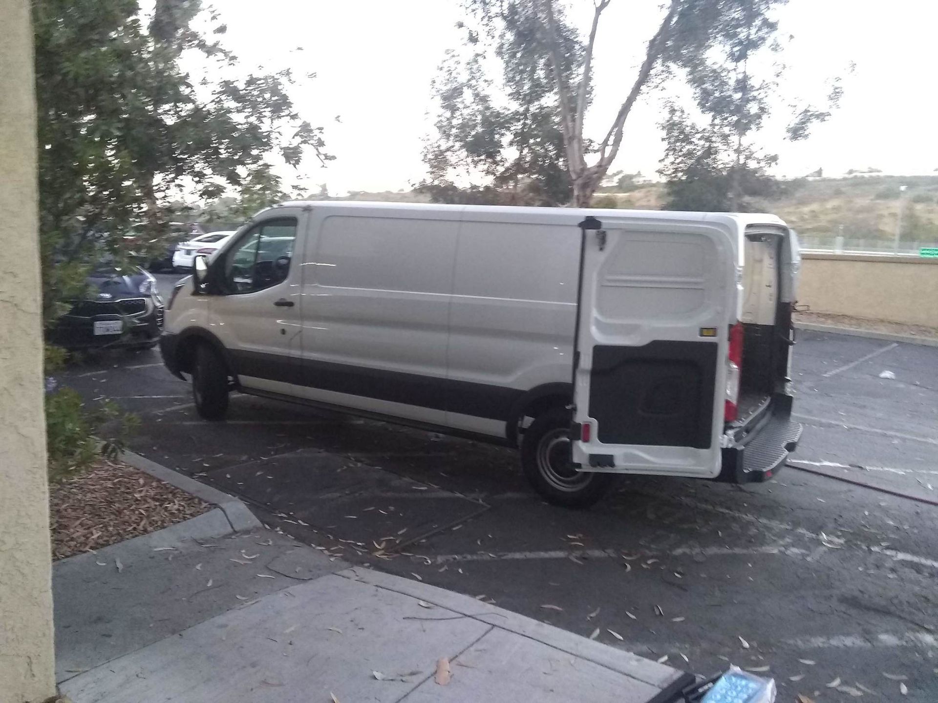 A white van is parked in a parking lot with the door open