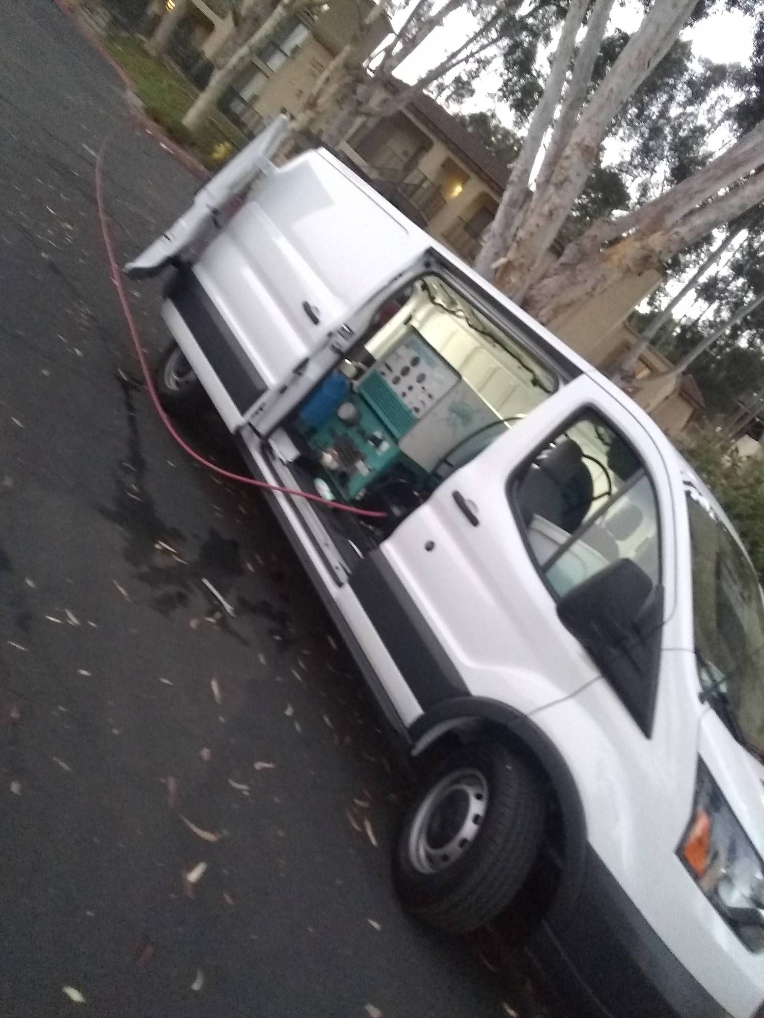 A white van is parked on the side of the road with its doors open