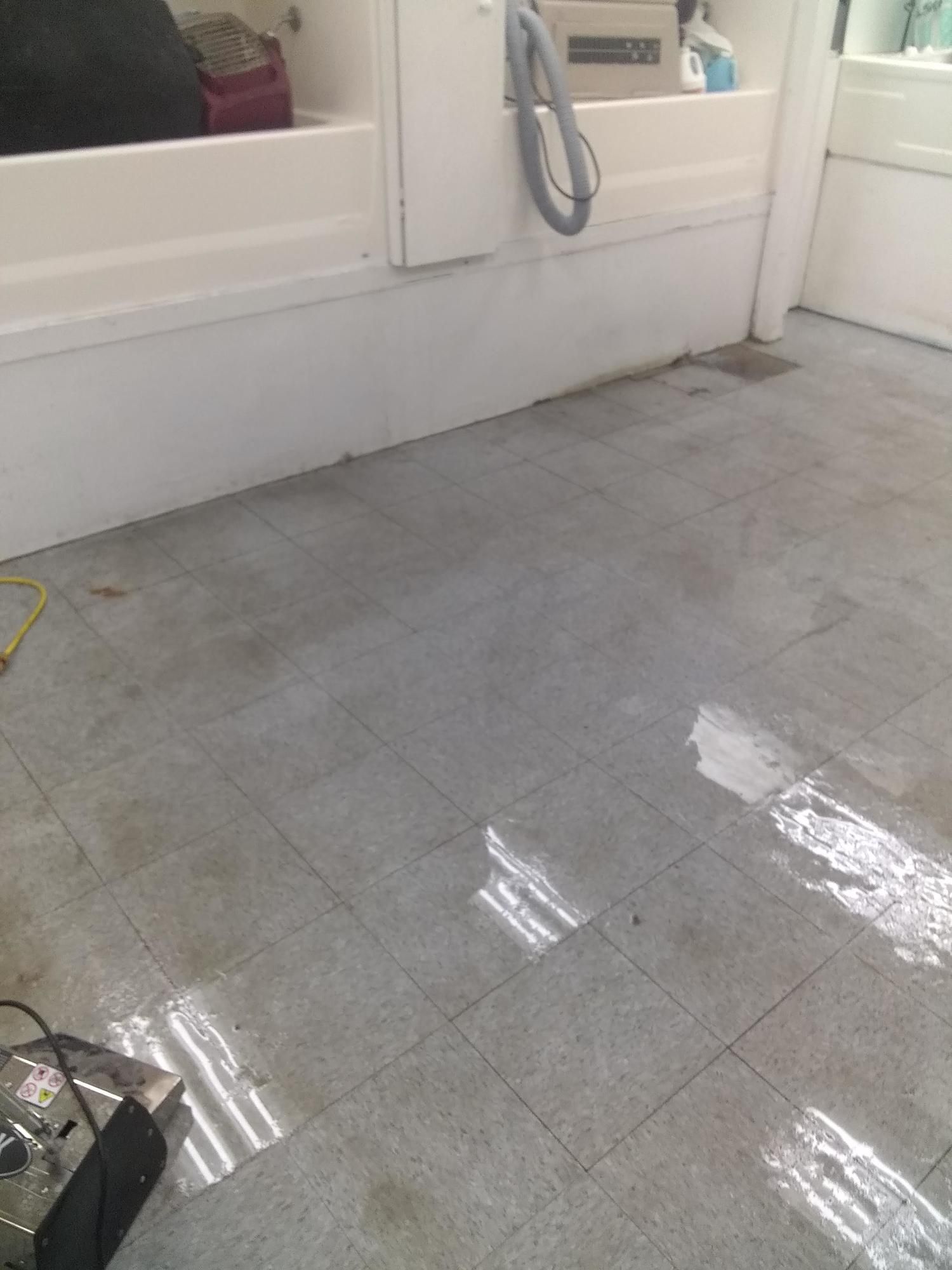 A dirty tiled floor in a bathroom next to a bathtub.
