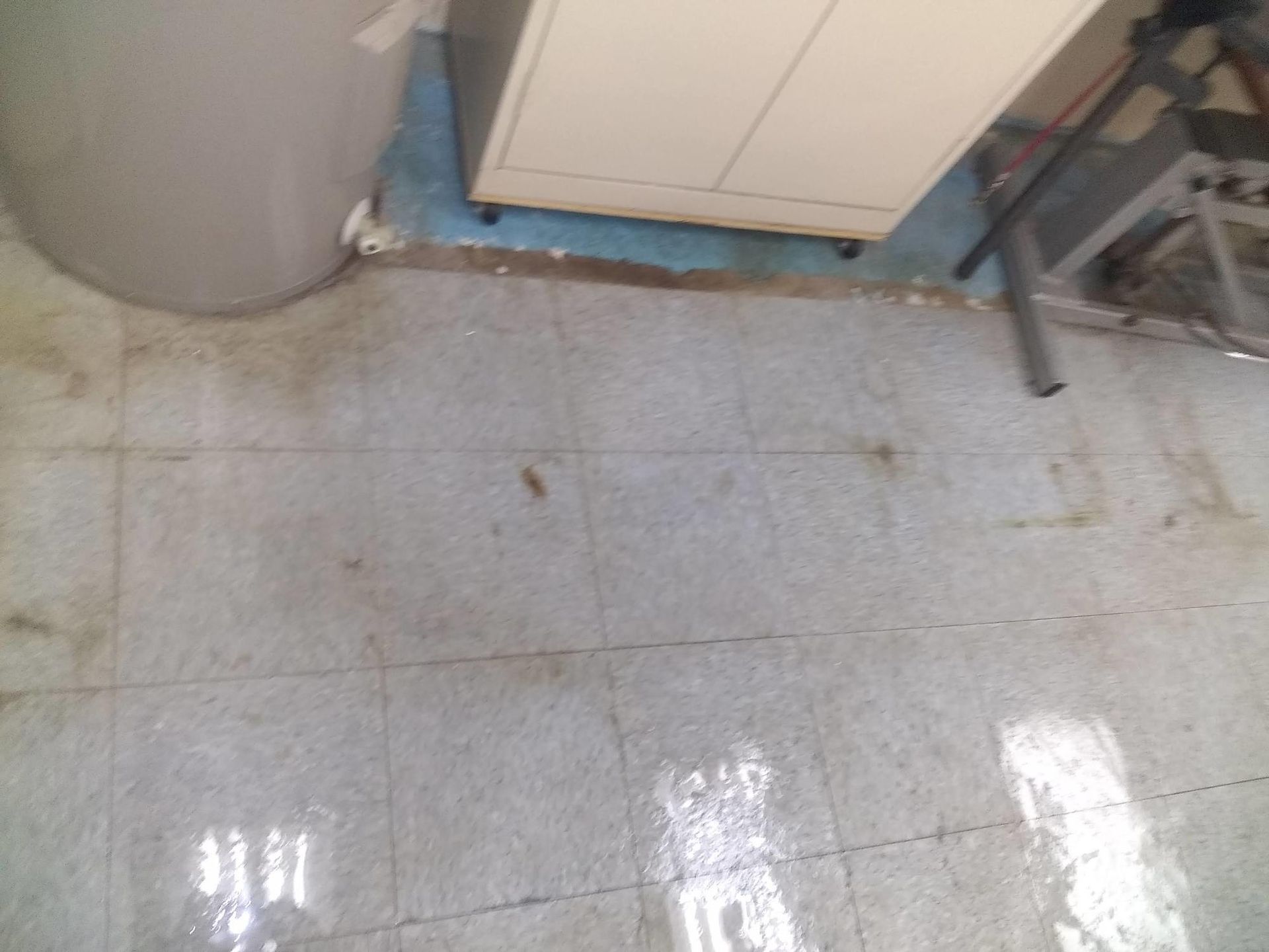 A dirty tiled floor in a room with a stove and a cabinet.