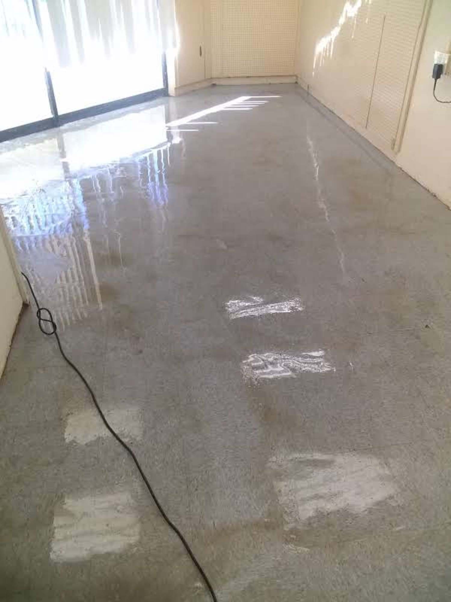 A room with a dirty floor and a sliding glass door.