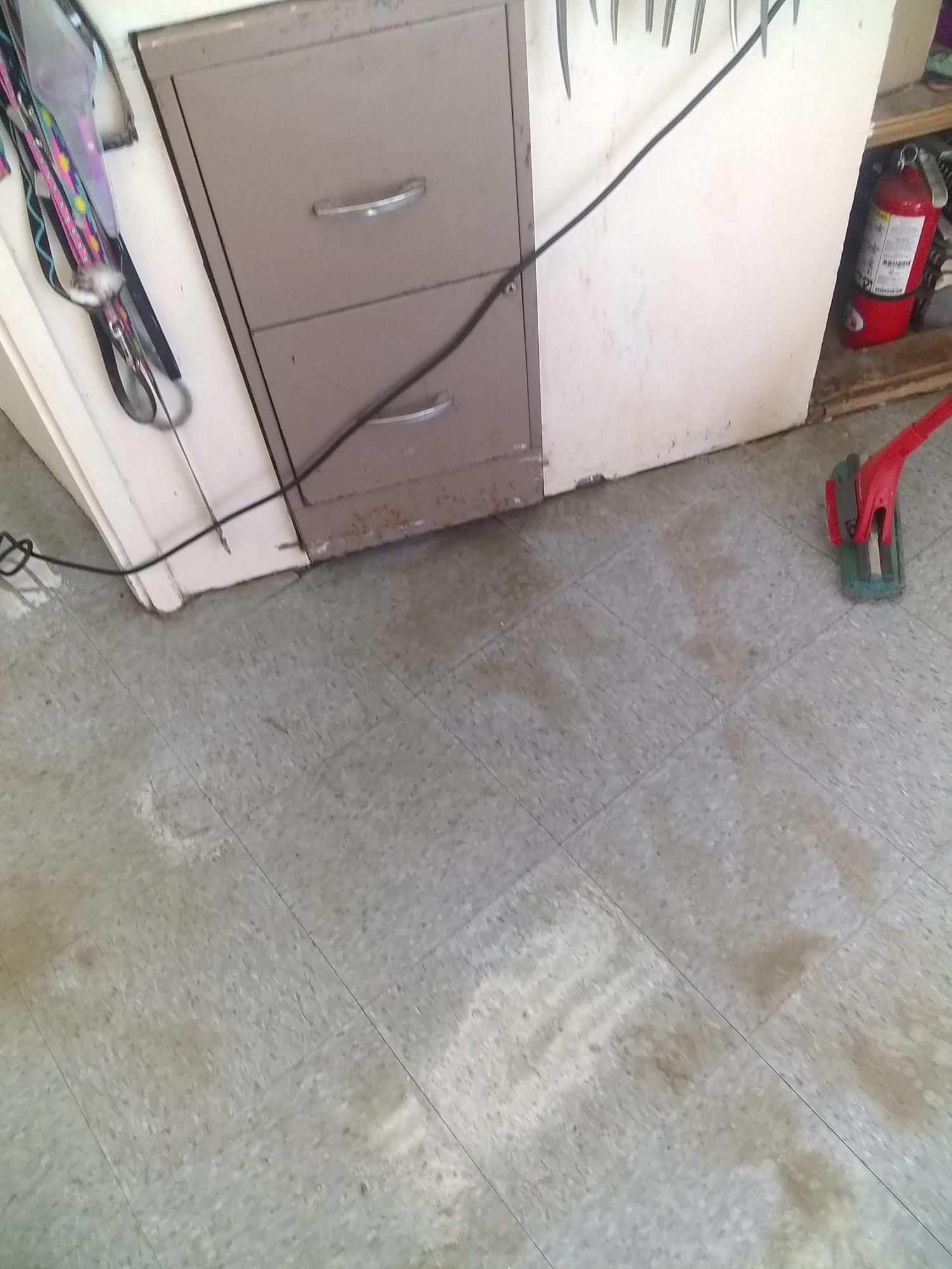 A dirty floor with a fire extinguisher in the background